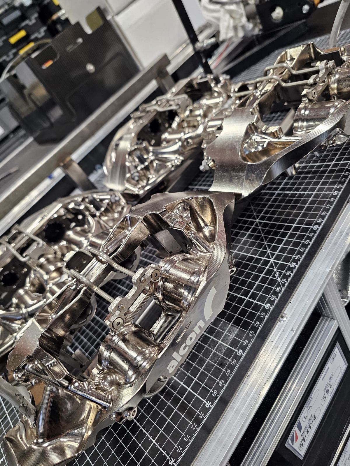 Machined race car parts laid out on a workshop rack