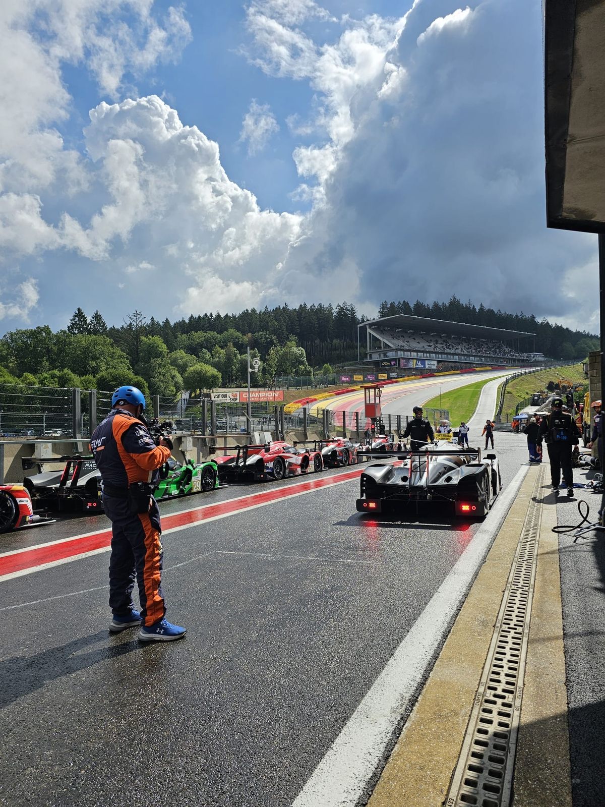 A mechanic waiting in the pit lane as race cars pass