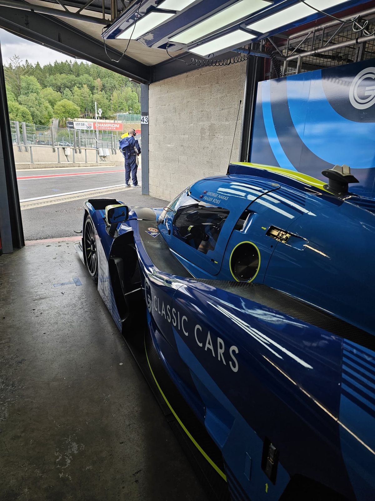 A prototype race car in a garage bay with the bodywork off