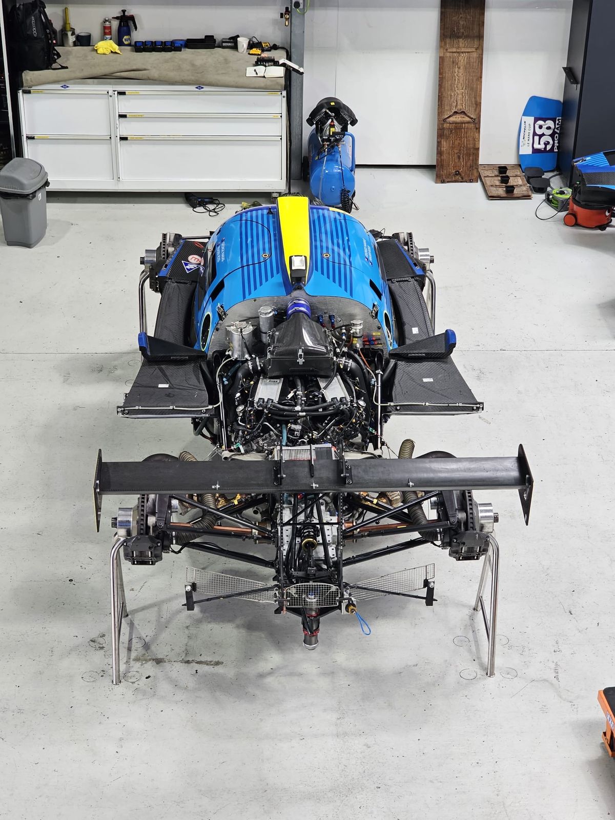 A mechanic working on a prototype race car in a team workshop